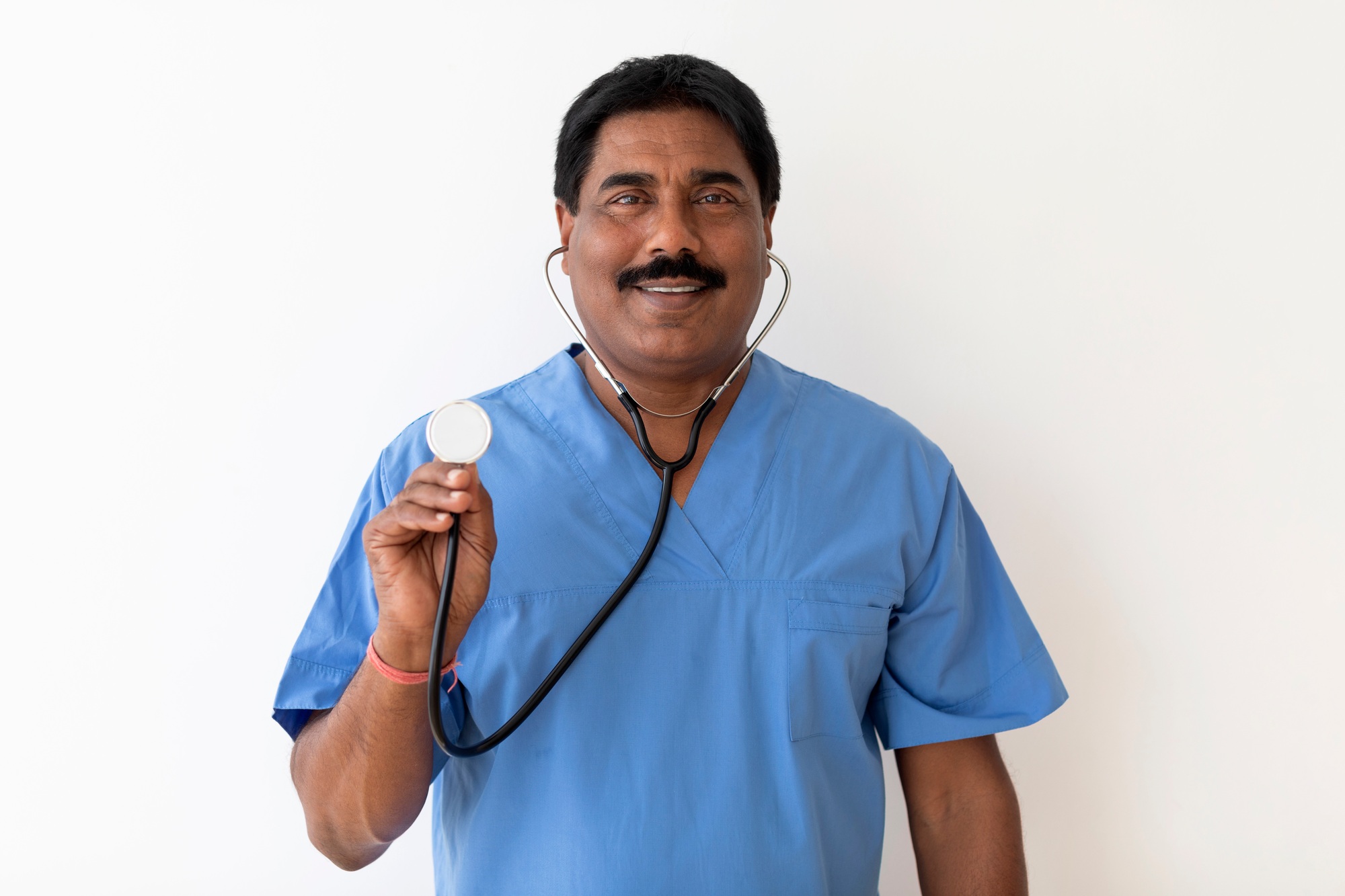 Smiling Indian Doctor Man With Stethoscope In Hand Posing Over White Background